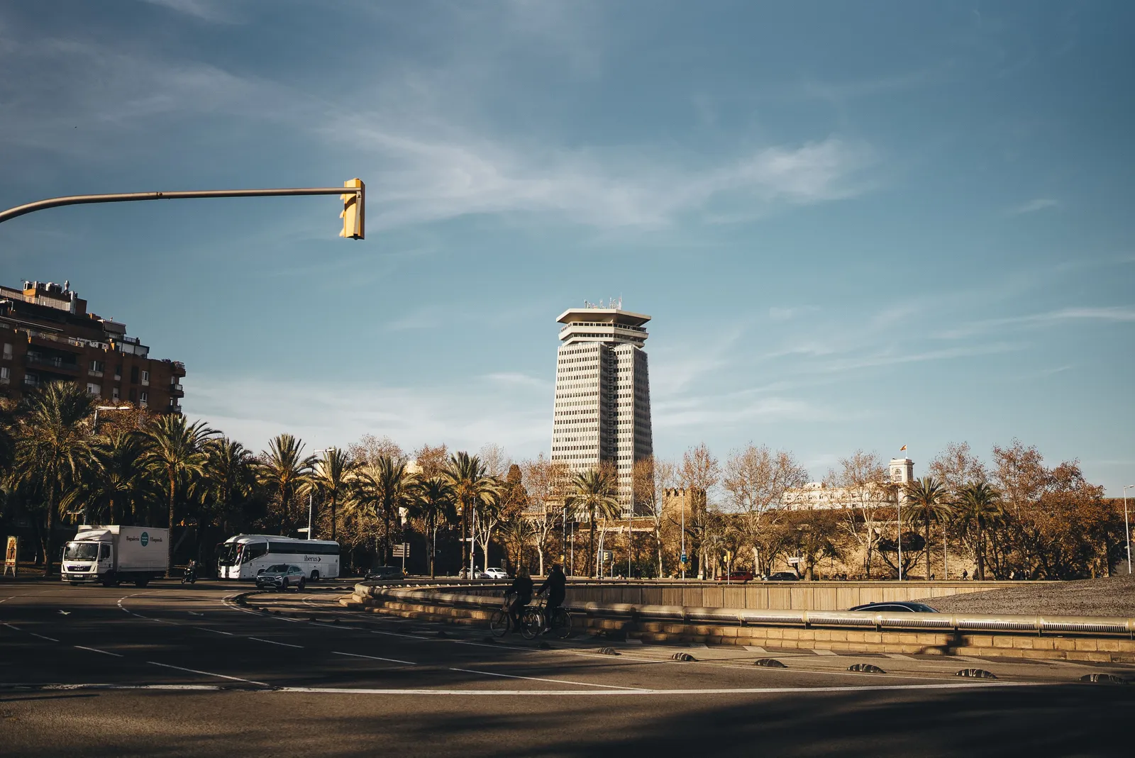 רחוב עירוני בברצלונה עם דקלים ותנועת אוטובוסים בדרך מהשדה למרכז, ספרד