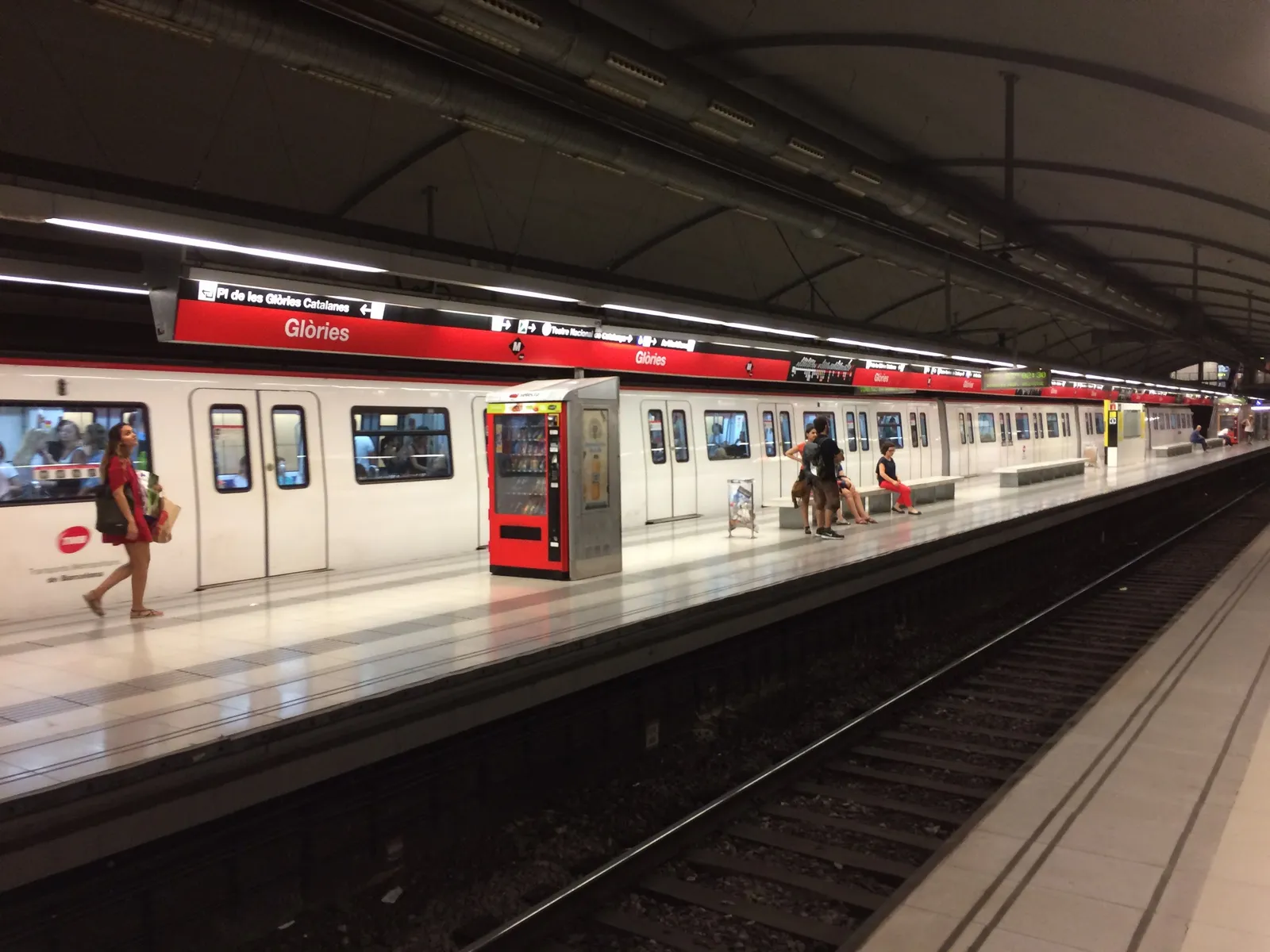 רציף מטרו בברצלונה עם נוסעים ממתינים ורכבת שנכנסת לתחנה