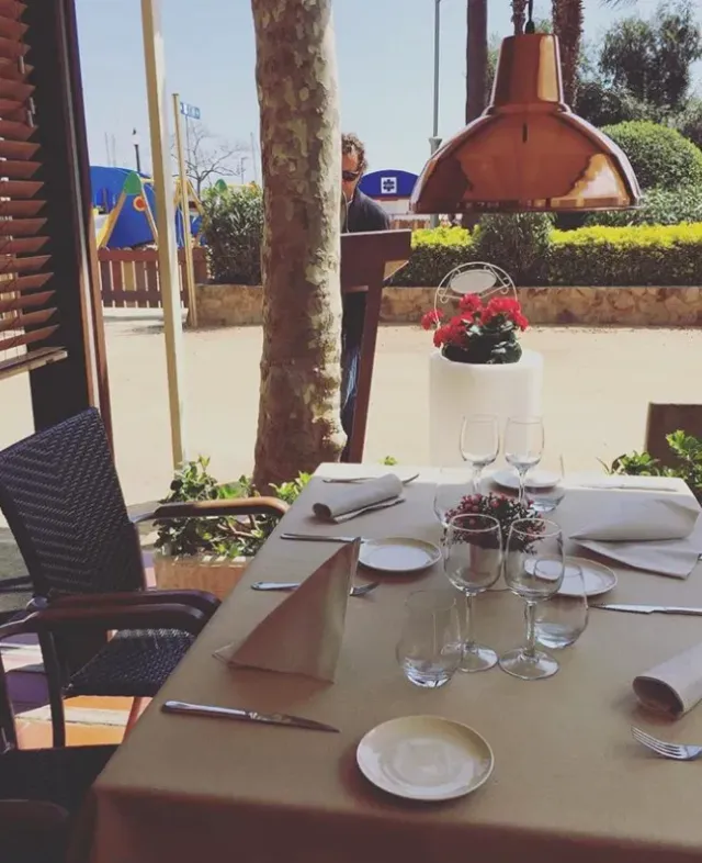 שולחן ערוך ליד חלון פתוח עם מנורת נחושת וגזע דקל בחוץ
