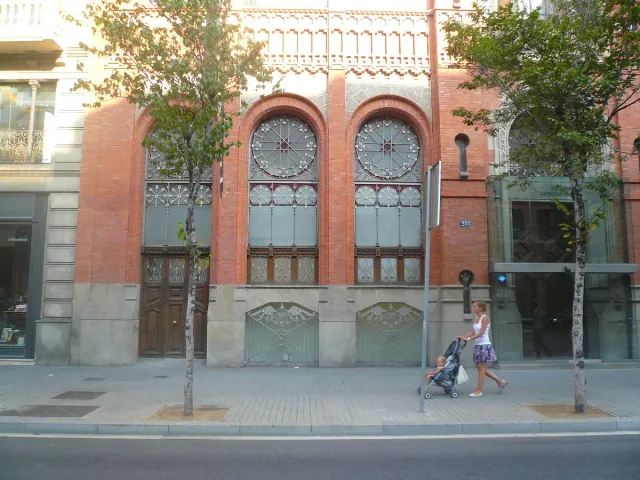 חזית לבנים אדומה עם חלונות מקושתים גבוהים מעל מדרכה עירונית