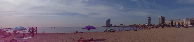 חוף חולי עם שמשייה סגולה ומלון בצורת מפרש באופק
