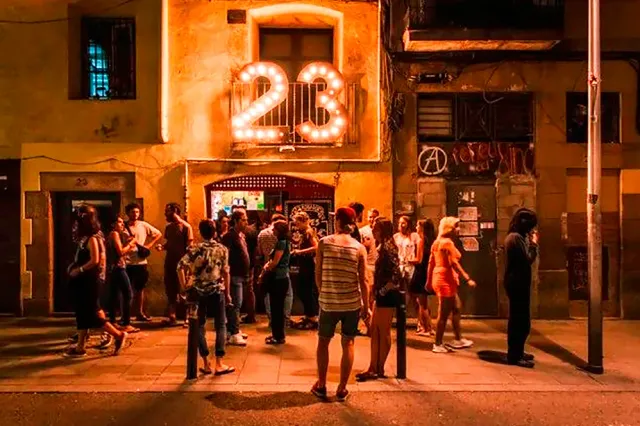 קהל עומד ברחוב בלילה מול חזית מוארת עם שלט נורות מספרי