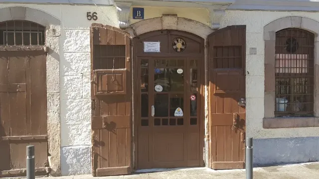דלת עץ חומה מקומרת במספר 56, עם מדבקות ותריסים סגורים לצדה